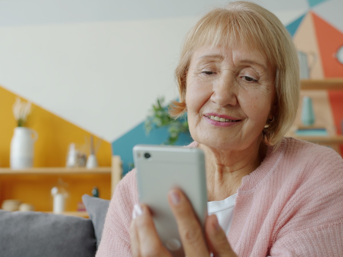 Persona mayor sonriendo mientras revisa una notificación en su teléfono